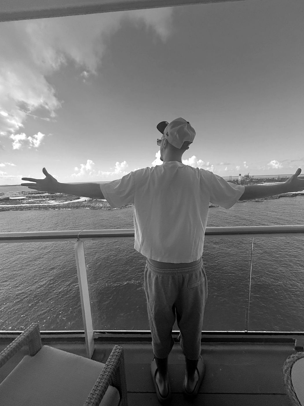 James Wilkins III on a balcony overlooking the ocean, arms outstretched